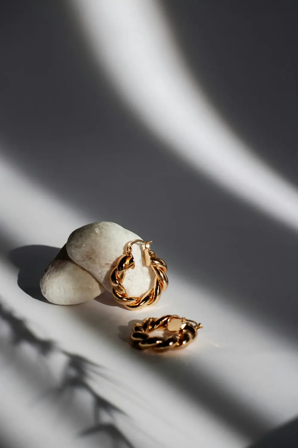 Gold hoop earrings resting on stone