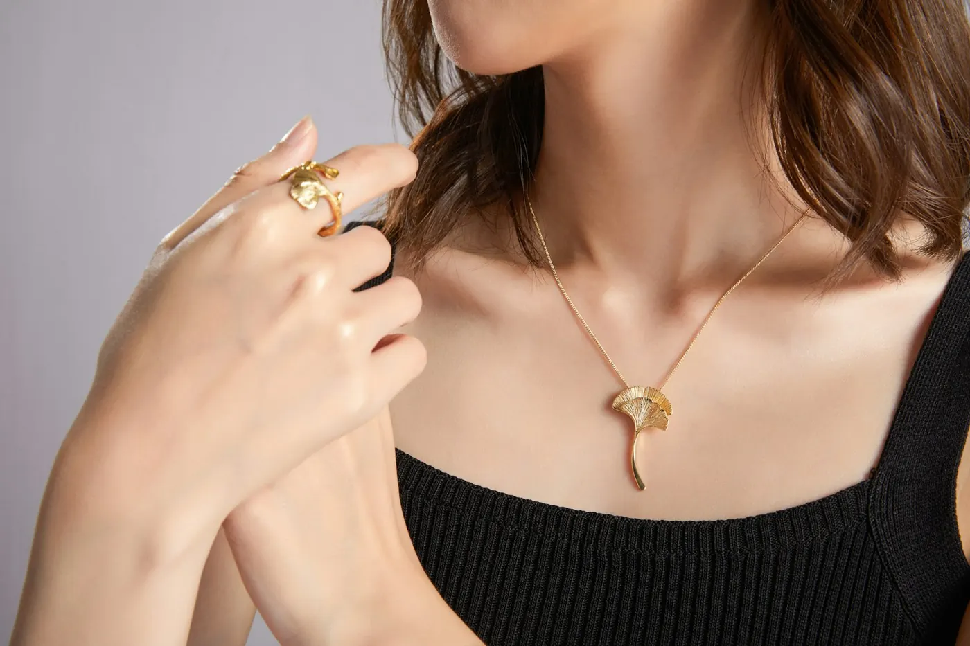 A woman wearing a gold pendant and ring